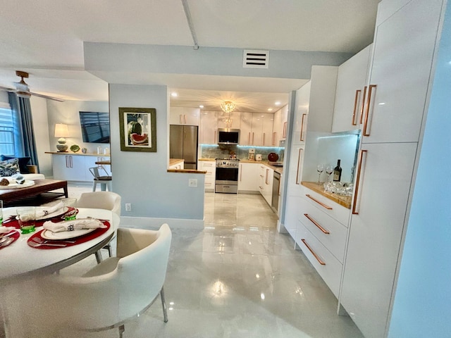 kitchen with backsplash, white cabinets, and stainless steel appliances