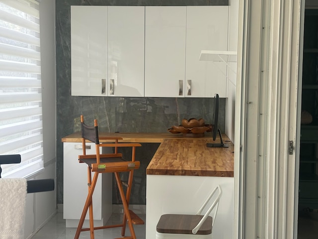 kitchen with backsplash, white cabinetry, and wood counters