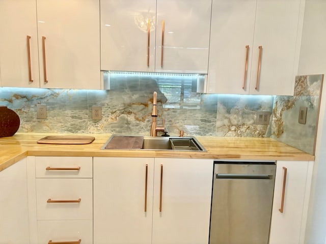 kitchen with white cabinets, decorative backsplash, wood counters, and sink