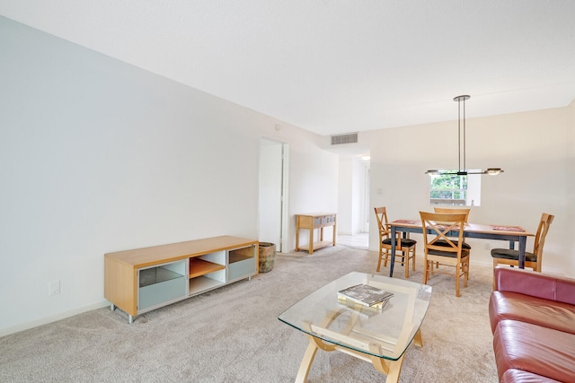 carpeted living room featuring an inviting chandelier