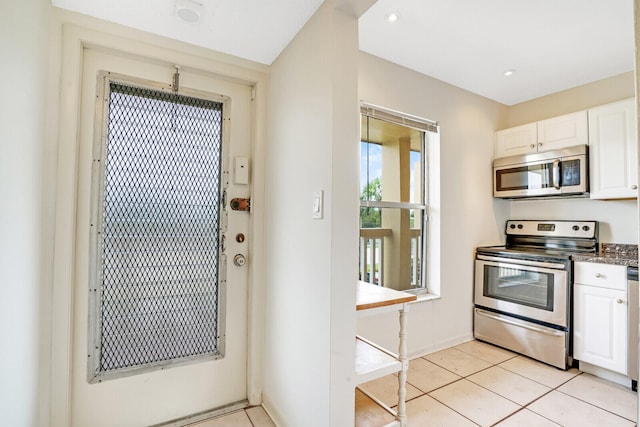 kitchen with stainless steel appliances, light tile flooring, and white cabinetry