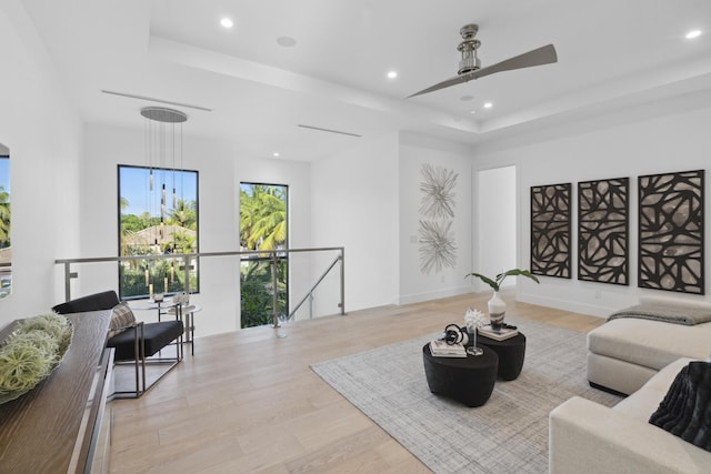 living area with recessed lighting, a raised ceiling, and wood finished floors