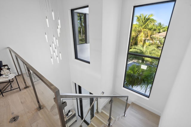 stairs with plenty of natural light, baseboards, and wood finished floors