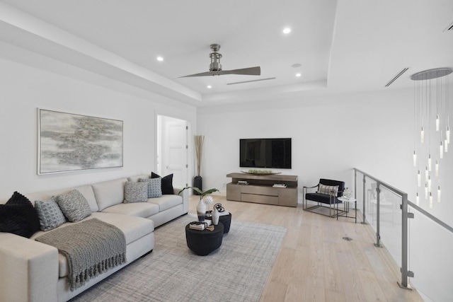 living room with visible vents, recessed lighting, ceiling fan, light wood-style floors, and a raised ceiling