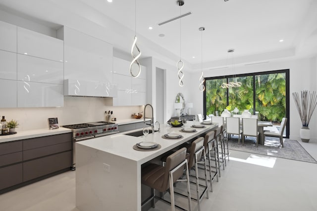 kitchen featuring a kitchen bar, modern cabinets, a sink, white cabinets, and range with two ovens