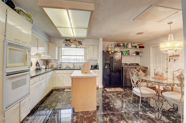 kitchen with white appliances, dark tile floors, pendant lighting, a notable chandelier, and a center island