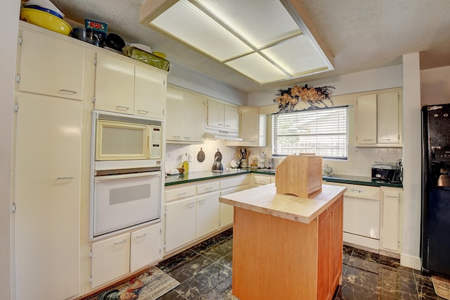 kitchen featuring white appliances, a kitchen island, dark tile flooring, and backsplash