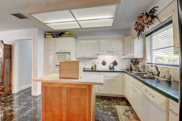 kitchen with sink, white dishwasher, dark tile flooring, tasteful backsplash, and exhaust hood