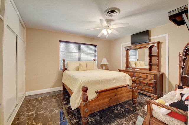 bedroom with a closet, ceiling fan, and dark tile flooring