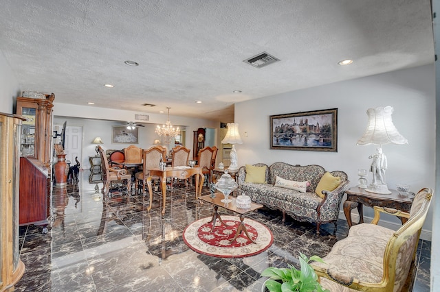 tiled living room featuring a textured ceiling and ceiling fan with notable chandelier