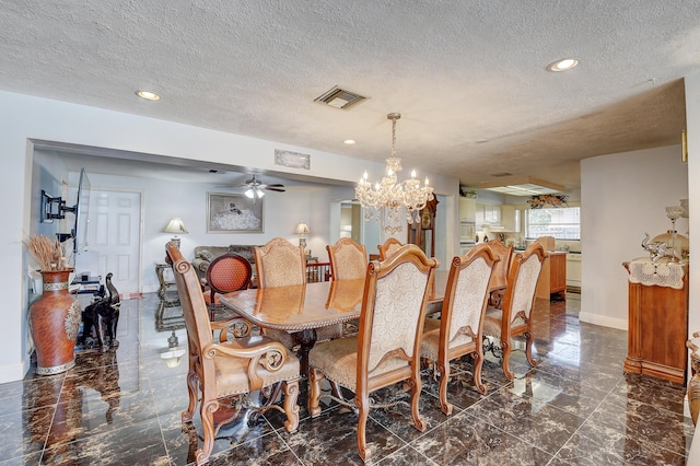 tiled dining area featuring a textured ceiling and ceiling fan with notable chandelier