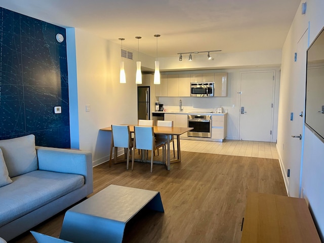 living room with light hardwood / wood-style floors, sink, and track lighting