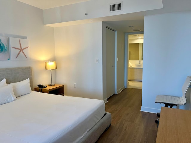 bedroom featuring dark wood-type flooring and ensuite bathroom