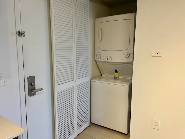 clothes washing area with light tile flooring and stacked washer and dryer