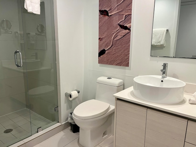 bathroom featuring toilet, large vanity, tile floors, and a shower with shower door