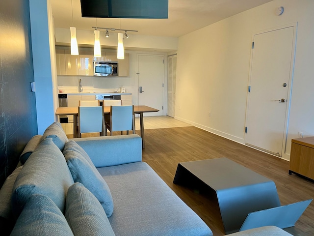 living room featuring sink, light wood-type flooring, and track lighting