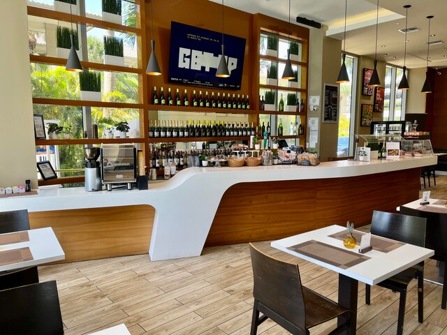 bar with hanging light fixtures, light hardwood / wood-style flooring, and a wealth of natural light