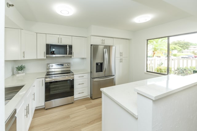 kitchen featuring appliances with stainless steel finishes, light hardwood / wood-style floors, sink, white cabinets, and light stone counters