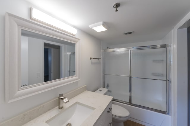 full bathroom featuring toilet, bath / shower combo with glass door, and vanity