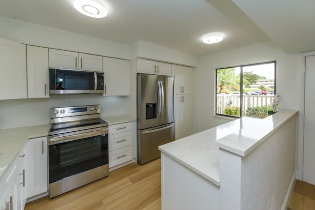 kitchen featuring white cabinets, light stone countertops, light hardwood / wood-style flooring, and appliances with stainless steel finishes