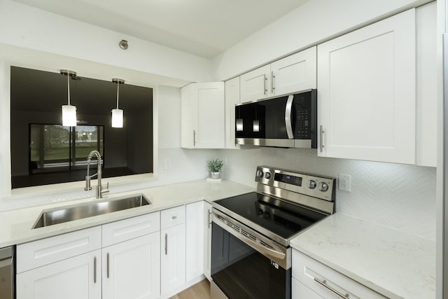 kitchen featuring hanging light fixtures, stainless steel appliances, white cabinetry, and sink