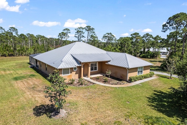 view of front of house with a front yard, a standing seam roof, metal roof, and stucco siding