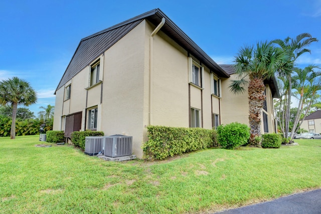 view of side of home featuring a lawn and central AC