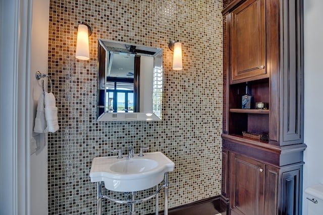 bathroom featuring sink, backsplash, toilet, and tile walls