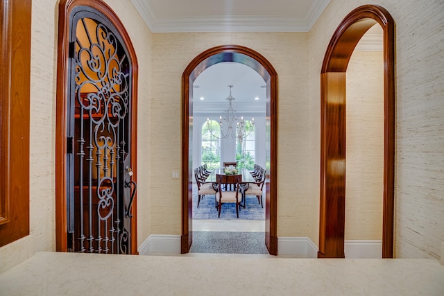 hallway with ornamental molding and a notable chandelier