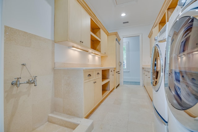 washroom featuring crown molding, separate washer and dryer, cabinets, and light tile flooring