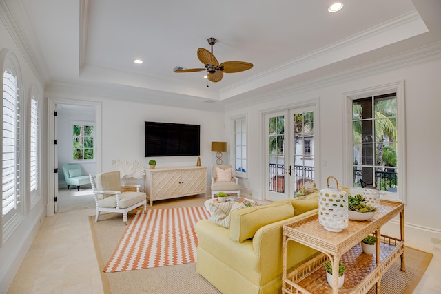 tiled living room with a raised ceiling, ornamental molding, and ceiling fan