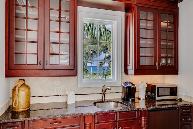 kitchen with dark stone countertops, backsplash, and sink