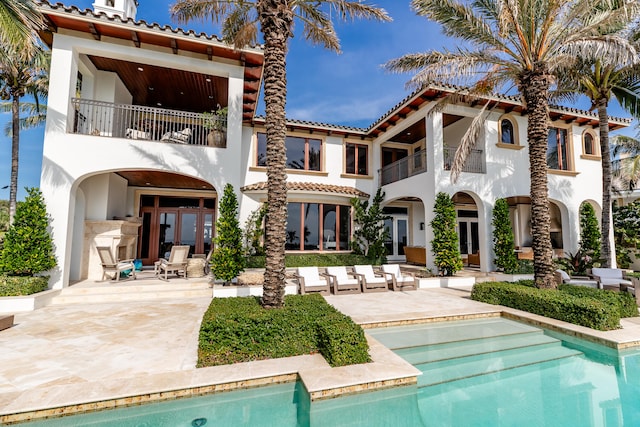 rear view of property with a balcony, french doors, and a patio