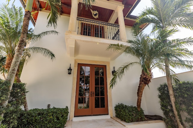 view of exterior entry with a balcony and french doors