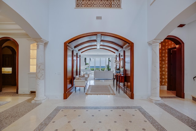 foyer featuring decorative columns and light tile flooring