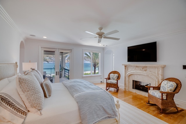 bedroom with a high end fireplace, crown molding, and light hardwood / wood-style flooring