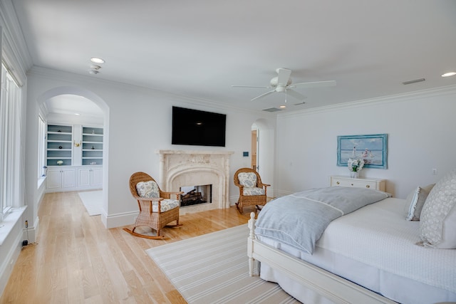 bedroom with a high end fireplace, light hardwood / wood-style floors, ceiling fan, and ornamental molding