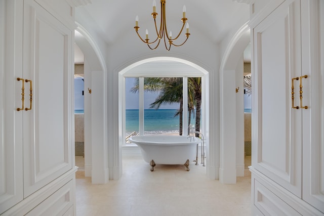 interior space featuring light tile floors, lofted ceiling, a chandelier, and a water view