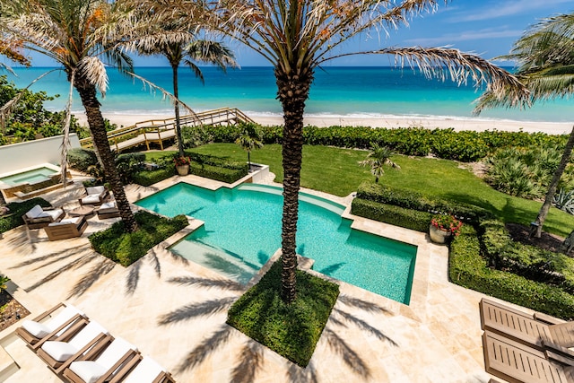 view of pool featuring a beach view, a water view, a lawn, and a patio area