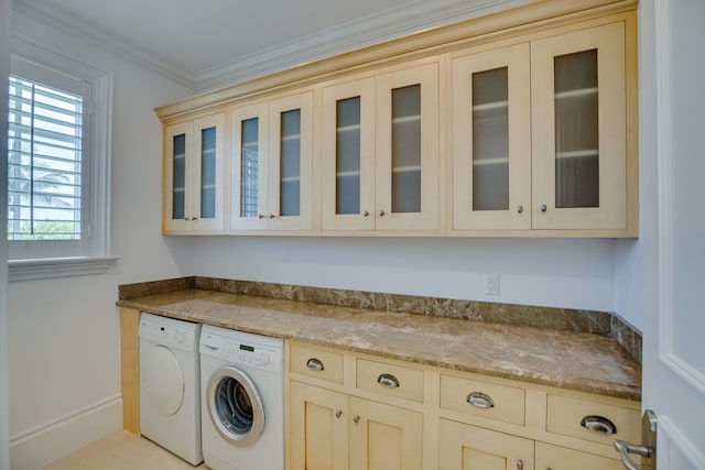 clothes washing area featuring washer and clothes dryer, cabinets, and ornamental molding