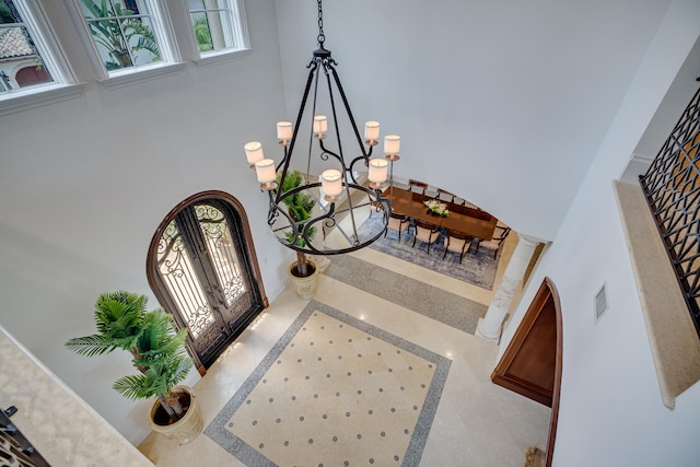 tiled foyer entrance with a chandelier, a high ceiling, and french doors