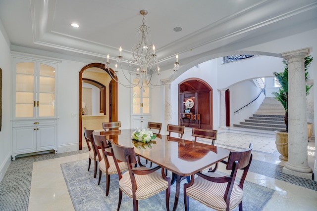 tiled dining room featuring a chandelier, a raised ceiling, and ornate columns