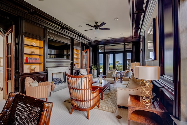 interior space featuring ceiling fan, built in features, a premium fireplace, crown molding, and light colored carpet