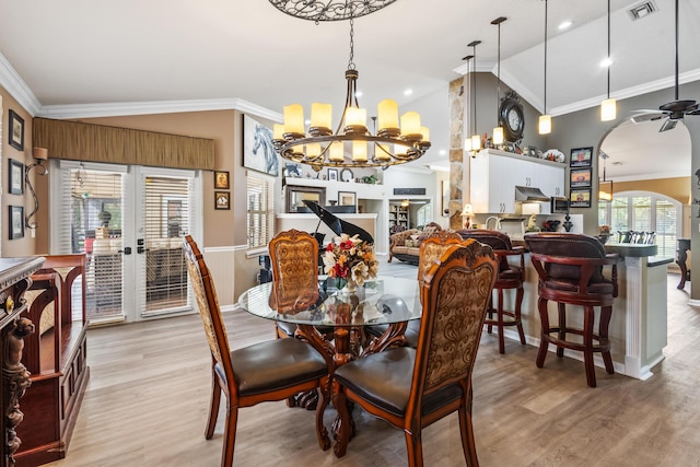 dining space featuring light wood-type flooring, lofted ceiling, and crown molding