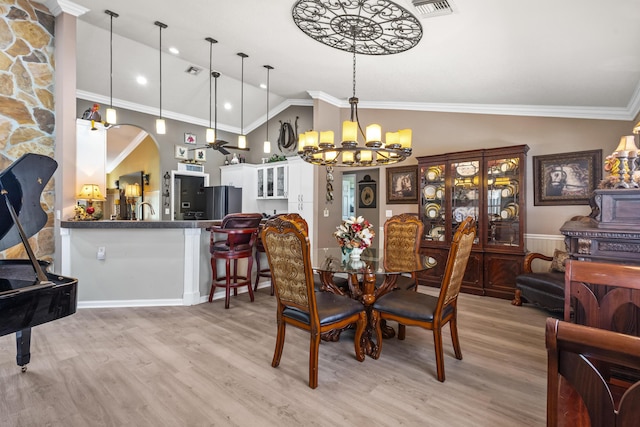 dining room with an inviting chandelier, light hardwood / wood-style floors, vaulted ceiling, and ornamental molding