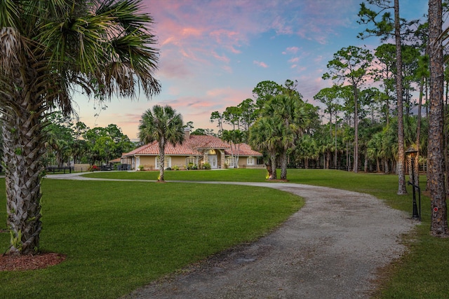 view of front facade featuring gravel driveway, a tile roof, and a front yard