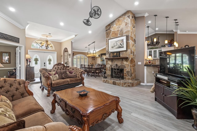 living room with a fireplace, a wealth of natural light, crown molding, and light wood-type flooring