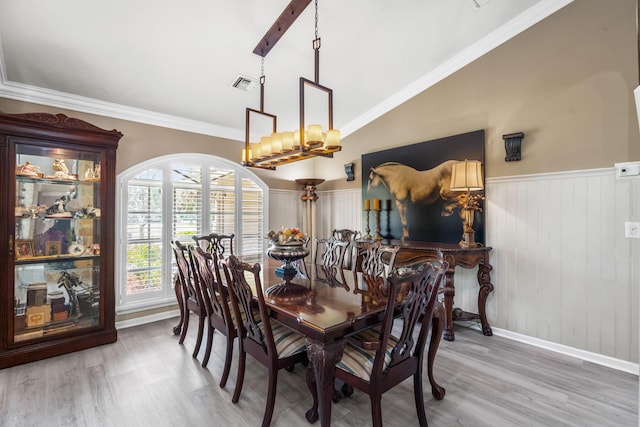 dining area with hardwood / wood-style floors, an inviting chandelier, lofted ceiling, and crown molding