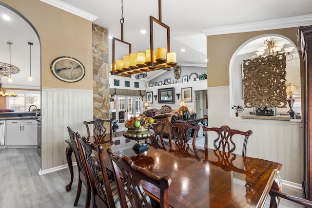 dining area with vaulted ceiling, crown molding, sink, wood-type flooring, and a notable chandelier