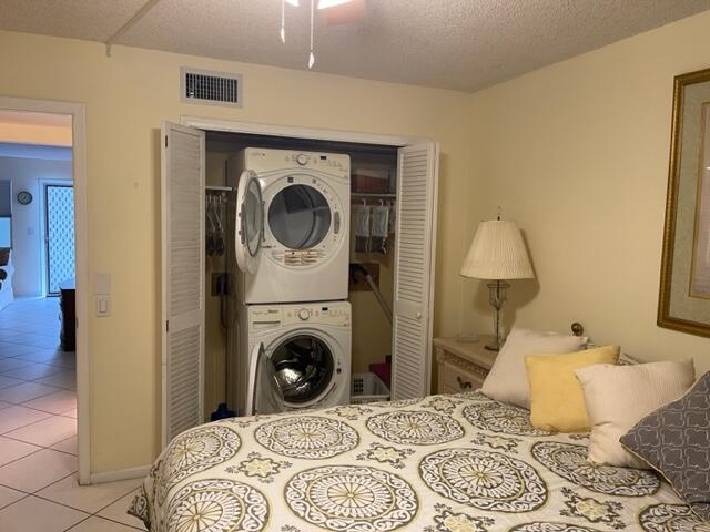 tiled bedroom featuring a closet and stacked washer / drying machine